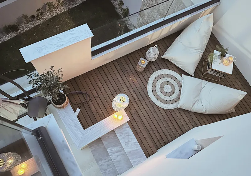 Sunny wooden deck with bean bags and greenery near olive grove in Gyalia House No. 3